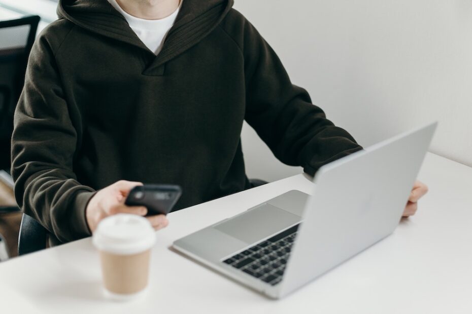 Man in a black hoodie working on a laptop